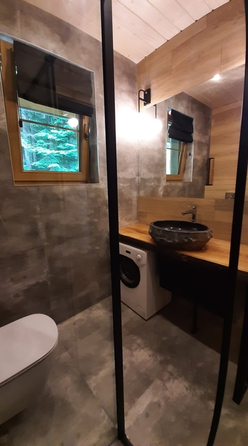 Zdjęcie z kabiny prysznicowej na blat z umywalką i duże lustro.