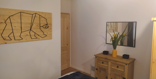 Bieszczady - Domek nad stawem - duża sypialnia, lustro, komoda i grafika niedźwiedź.