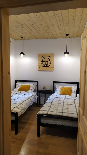 Widok na łóżka w sypialni nr 2. Grafika na ścianie - miś.